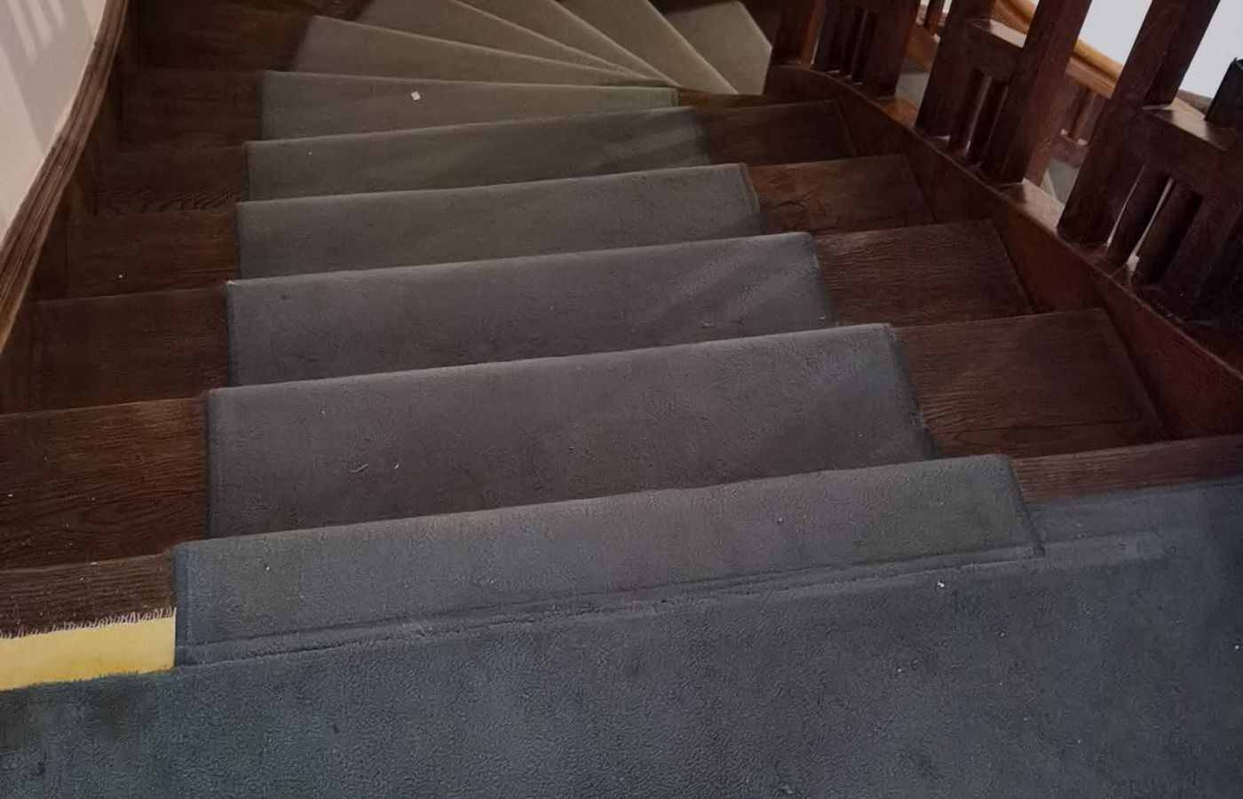 Gewendelte Holztreppe mit altem, abgenutztem Belag vor der Sanierung