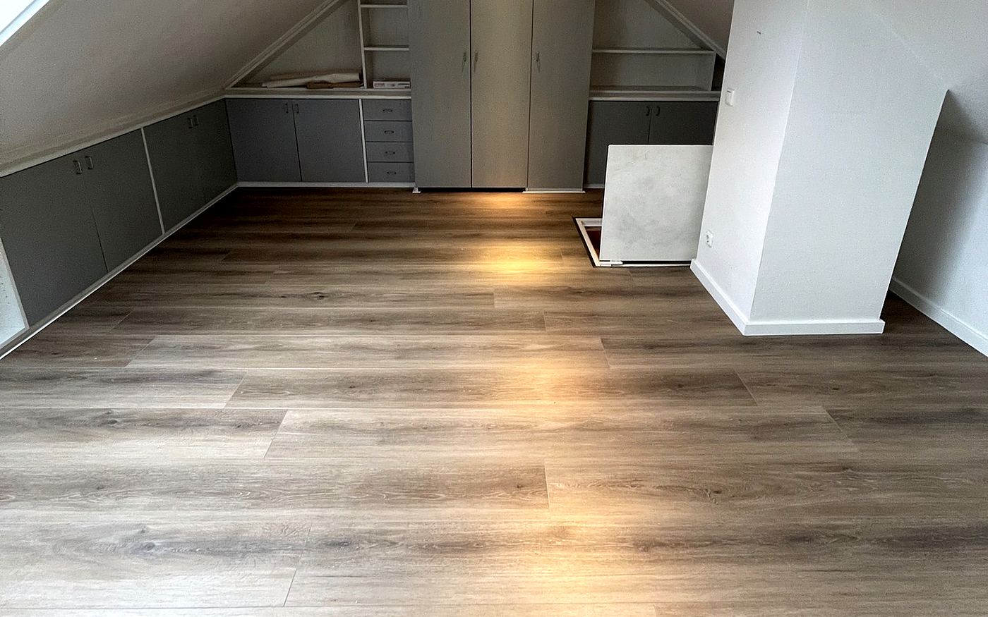 Dachgeschosszimmer mit grauem Designboden und Einbauschränken