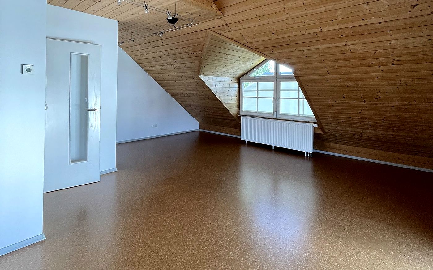 Dachraum mit Korkboden, Gaube und weißer Tür in München