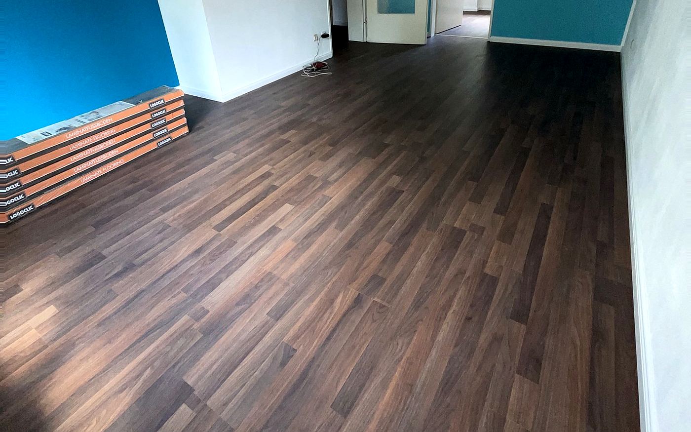 Dunkles Laminat in einem Raum mit türkisfarbener Wand