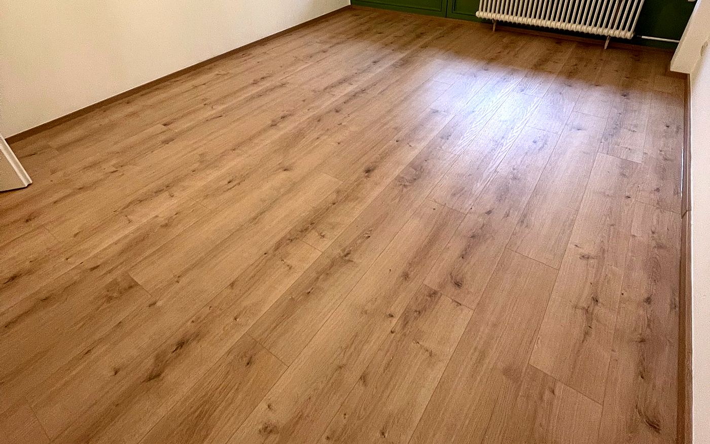 Zimmer mit hellem Eichen-Laminat und Fenster mit Blick ins Grüne