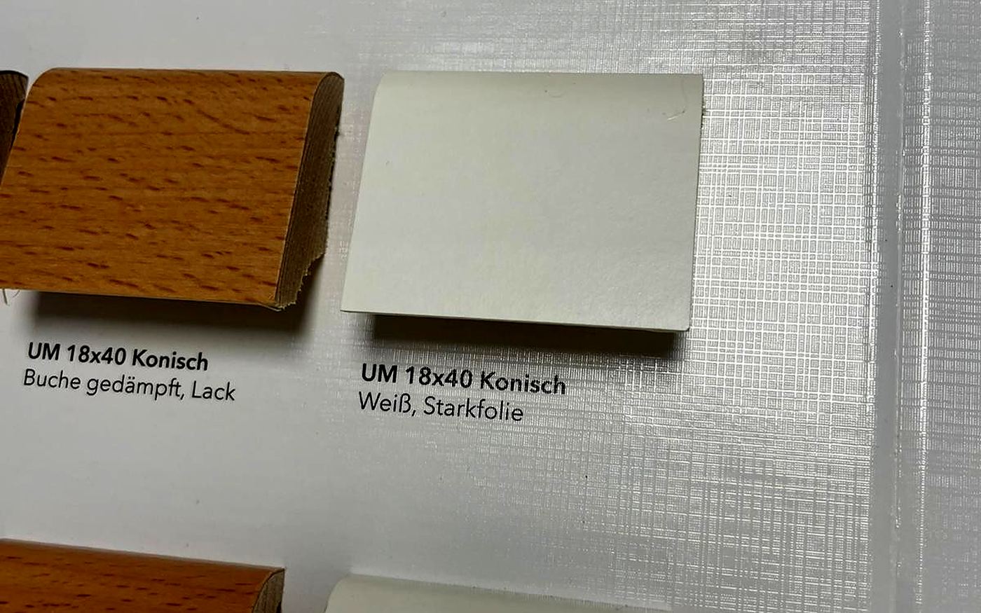 Zwei Sockelleistenprofile als Muster mit Beschriftung an der Wand