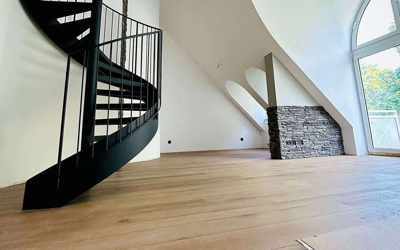 Schwarze Wendeltreppe in einem hellen Raum mit hellem Holzboden in München